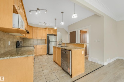 Kitchen featuring light wood-finish cabinetry, granite countertops, tile backsplash, and stainless steel appliances - 10234 155 Street Nw, Edmonton, AB - Indoor Photo Showing Kitchen