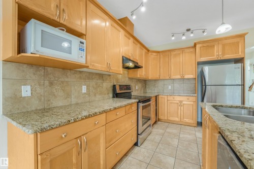 Full kitchen featuring light wood cabinetry, stone countertops, stainless steel appliances, and tile flooring - 10234 155 Street Nw, Edmonton, AB - Indoor Photo Showing Kitchen With Double Sink