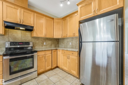 Stainless steel appliances, wood-finish cabinetry, tile flooring, tile backsplash, and speckled countertops - 10234 155 Street Nw, Edmonton, AB - Indoor Photo Showing Kitchen