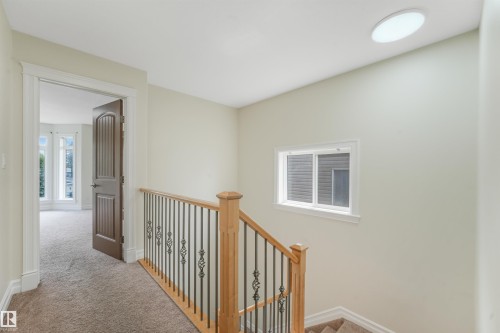 Hardwood newel posts, wrought iron balusters, and a contemporary flush-mount ceiling light - 10234 155 Street Nw, Edmonton, AB - Indoor Photo Showing Other Room