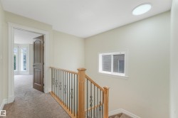 Hardwood newel posts, wrought iron balusters, and a contemporary flush-mount ceiling light - 