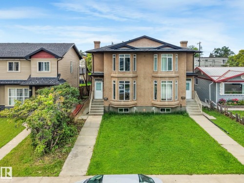 Duplex featuring a stucco exterior, multiple bay windows, individual front entries, and a shingled roof - 10234 155 Street Nw, Edmonton, AB - Outdoor With Facade