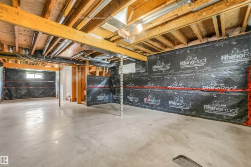 Unfinished basement with concrete flooring, exposed wood ceiling joists, and a small window - 10234 155 Street Nw, Edmonton, AB - Indoor Photo Showing Basement