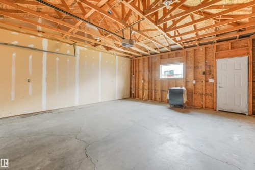 Spacious garage interior with exposed rafter ceiling, concrete flooring, and framed wall construction - 10234 155 Street Nw, Edmonton, AB - Indoor Photo Showing Basement