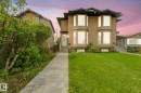 Stucco exterior with multiple bay windows, black trim, concrete pathway, and a front lawn - 10234 155 Street Nw, Edmonton, AB  - Outdoor With Facade 