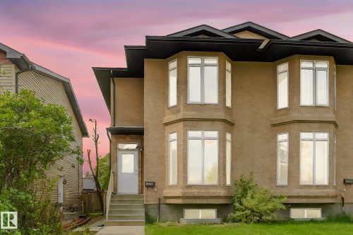 Stucco exterior featuring multiple bay windows, a prominent dark roofline, and a concrete pathway leading to the entry - 10234 155 Street Nw, Edmonton, AB - Outdoor With Facade
