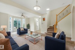 Bay window with multiple panes, ceiling fan, carpeted staircase with wood handrail and wrought iron balusters, recessed lighting, and a front entry door with glass panels - 