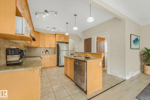 Kitchen with wood cabinetry, stainless steel appliances, granite countertops, and tiled flooring - 10234 155 Street Nw, Edmonton, AB - Indoor Photo Showing Kitchen