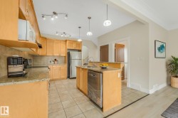 Kitchen with wood cabinetry, stainless steel appliances, granite countertops, and tiled flooring - 