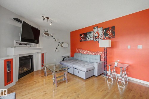 Wood-finish flooring throughout, with a built-in fireplace featuring a white mantel and integrated shelving - 9935 155 Street Nw, Edmonton, AB - Indoor With Fireplace
