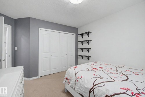 Neutral tone wall with a contrasting accent wall, ceiling-mounted light fixture, and bifold closet doors - 9935 155 Street Nw, Edmonton, AB - Indoor Photo Showing Bedroom