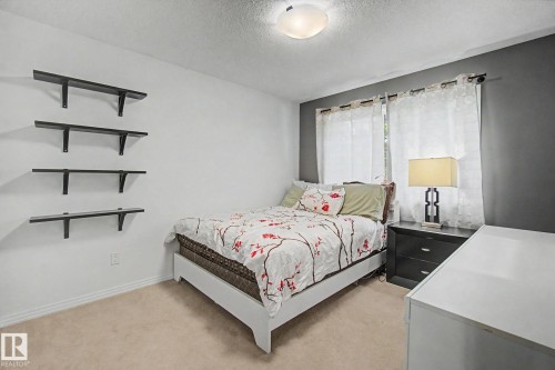 Carpeted flooring, white walls with an accent wall, and built-in wall shelves - 9935 155 Street Nw, Edmonton, AB - Indoor Photo Showing Bedroom
