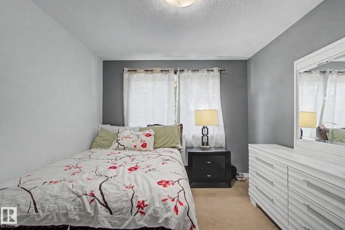 Neutral wall paint, ceiling-mounted light fixture, window with privacy sheers, carpeted flooring, and a mirrored dresser - 9935 155 Street Nw, Edmonton, AB - Indoor Photo Showing Bedroom