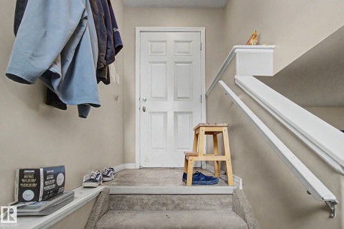 Panel door entry with a tile-finish landing, flanked by a carpeted staircase with a white handrail - 9935 155 Street Nw, Edmonton, AB - Indoor Photo Showing Other Room
