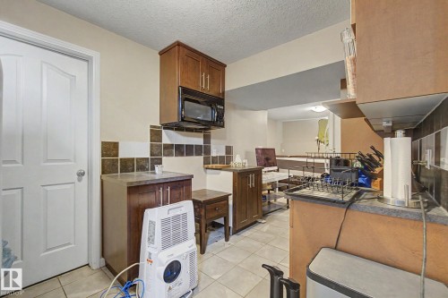 Kitchenette featuring wood-finish cabinetry, tile flooring, and a built-in microwave - 9935 155 Street Nw, Edmonton, AB - Indoor