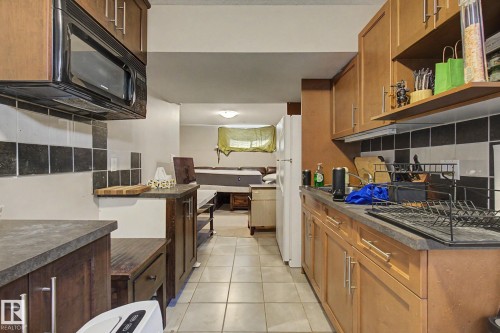 Kitchenette featuring wood-finish cabinetry, dark countertops, a built-in microwave, and tile flooring - 9935 155 Street Nw, Edmonton, AB - Indoor Photo Showing Kitchen
