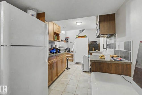 Tile flooring with wood-finish cabinetry and a tiled backsplash - 9935 155 Street Nw, Edmonton, AB - Indoor Photo Showing Kitchen