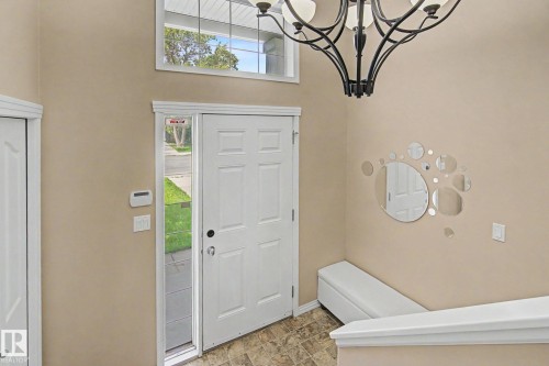 Foyer featuring a paneled entry door with sidelight, transom window, and a decorative chandelier - 9935 155 Street Nw, Edmonton, AB - Indoor Photo Showing Other Room