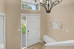 Foyer featuring a paneled entry door with sidelight, transom window, and a decorative chandelier - 
