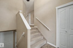 Carpeted staircase with white handrails, white interior doors, and neutral wall tones - 