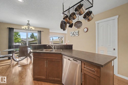 Kitchen island with integrated stainless steel dishwasher, wood-finish cabinetry, and a double basin sink - 9935 155 Street Nw, Edmonton, AB - Indoor Photo Showing Kitchen With Double Sink