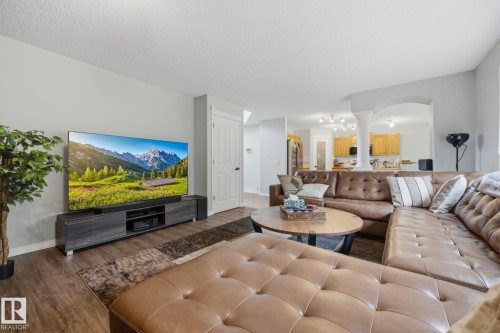 Wood-finish flooring, light gray wall tones, and an arched entryway with decorative columns - 15 Orchid Place, St. Albert, AB - Indoor Photo Showing Living Room