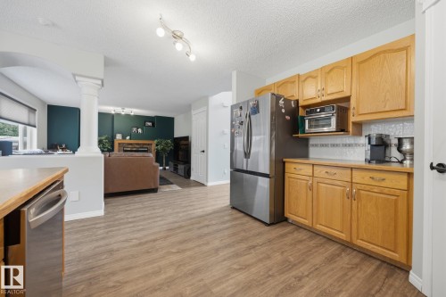 Kitchen featuring wood-finish flooring, light wood cabinetry, white tile backsplash, and stainless steel appliances - 15 Orchid Place, St. Albert, AB - Indoor Photo Showing Kitchen
