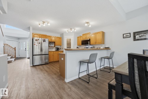 Kitchen featuring wood-finish flooring, stainless steel appliances, light wood cabinetry, and a breakfast bar - 15 Orchid Place, St. Albert, AB - Indoor Photo Showing Other Room
