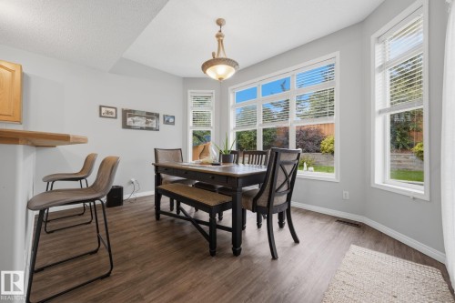 Recessed bay window, wood-finish flooring, wood cabinetry, built-in breakfast bar, and a chandelier fixture - 15 Orchid Place, St. Albert, AB - Indoor Photo Showing Dining Room