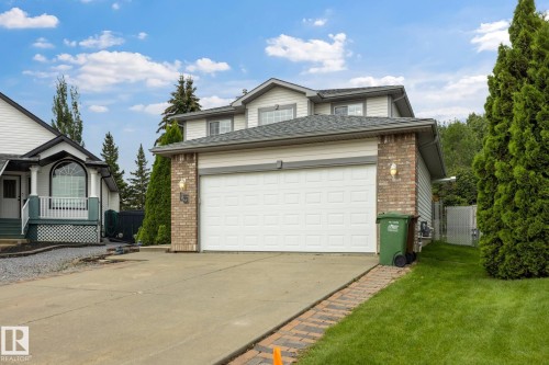 Two-story residence featuring a two-car garage, brick façade accents, and a concrete driveway - 15 Orchid Place, St. Albert, AB - Outdoor