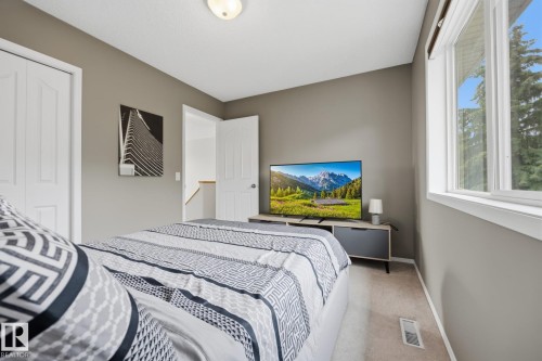 Neutral-toned walls complement a window with natural light and a built-in closet with panel doors - 15 Orchid Place, St. Albert, AB - Indoor Photo Showing Bedroom
