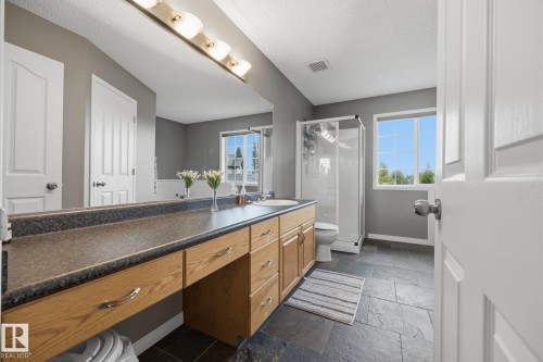 Dual vanity with wood-finish cabinetry and a large mirror - 15 Orchid Place, St. Albert, AB - Indoor Photo Showing Bathroom