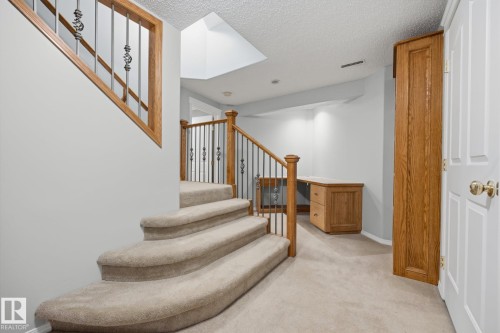 Carpeted staircase with wood banister and wrought iron spindles - 15 Orchid Place, St. Albert, AB - Indoor Photo Showing Other Room
