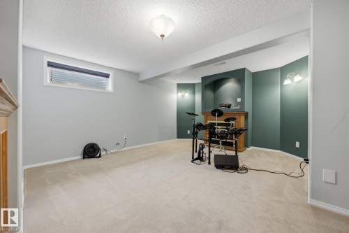 Carpeted room featuring a built-in fireplace with a wood-finish mantel and a recessed niche, recessed lighting, and wall-mounted sconces - 15 Orchid Place, St. Albert, AB - Indoor
