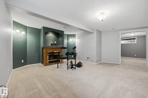 Expansive carpeted room featuring a built-in fireplace with a wood-finish mantel and a recessed niche - 15 Orchid Place, St. Albert, AB - Indoor