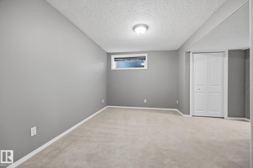 Soft gray walls, light-toned carpeting, white bi-fold closet doors, and an egress window - 15 Orchid Place, St. Albert, AB - Indoor Photo Showing Other Room