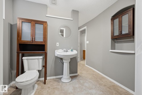 Spacious bathroom featuring a pedestal sink with chrome faucet, ceramic tile flooring, and abundant natural light from recessed ceiling fixtures - 15 Orchid Place, St. Albert, AB - Indoor Photo Showing Bathroom