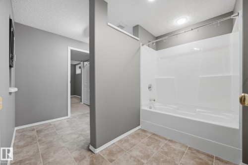 White acrylic tub and shower combination with chrome fixtures, complemented by tile flooring and gray wall tones - 15 Orchid Place, St. Albert, AB - Indoor Photo Showing Bathroom