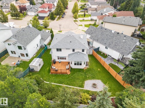 Expansive backyard featuring a wood deck, manicured lawn, stone fire pit, and mature trees - 15 Orchid Place, St. Albert, AB - Outdoor With View