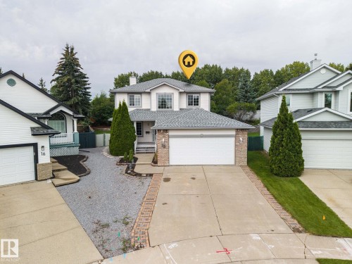 Two-story residence featuring light-colored siding, a prominent front entrance, an attached garage, and a concrete driveway bordered by brick pavers - 15 Orchid Place, St. Albert, AB - Outdoor With Facade