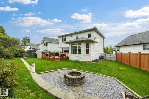 Manicured lawn with a stone-edged gravel area featuring a built-in fire pit - 15 Orchid Place, St. Albert, AB - Outdoor With Backyard With Exterior