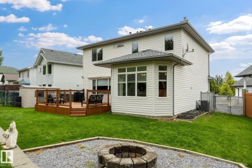 Expansive backyard featuring a wood deck with railings, a built-in stone fire pit, a sunroom extension, and a storage shed - 15 Orchid Place, St. Albert, AB - Outdoor With Deck Patio Veranda With Exterior