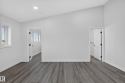 Living Space # 1Spacious room featuring wood-finish flooring, white trim, and a vaulted ceiling - 