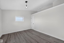 Living Space # 1 Spacious room featuring wood-finish flooring, white baseboards, and light gray painted walls - 