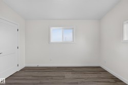 Living Space # 1 Interior space featuring wood-finish flooring, white baseboards, and a white paneled door with black hardware - 