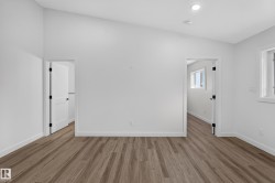 Living Space # 2 Spacious room featuring vaulted ceilings, wood-finish flooring, two panel doors with matte black hardware, recessed lighting, and a white framed window - 