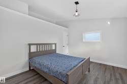 Living Space # 2  Spacious interior featuring wood-finish flooring, white walls, and a contemporary pendant light fixture - 