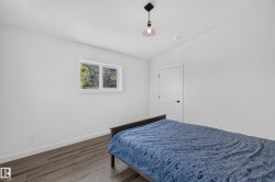 Living Space # 2  Bright room with wood-finish flooring, white walls, and a contemporary pendant light fixture - 
