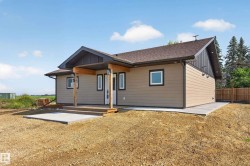 Modern bungalow featuring tan horizontal siding, a covered wooden porch with exposed beams, and dark trim accents - 