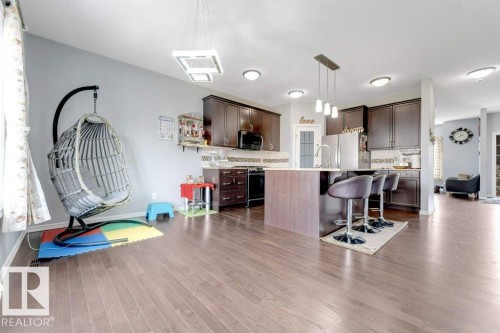 Open-concept kitchen and living area featuring wood-finish flooring, recessed lighting, and a kitchen island with a breakfast bar - 2436 18 Avenue Nw, Edmonton, AB 